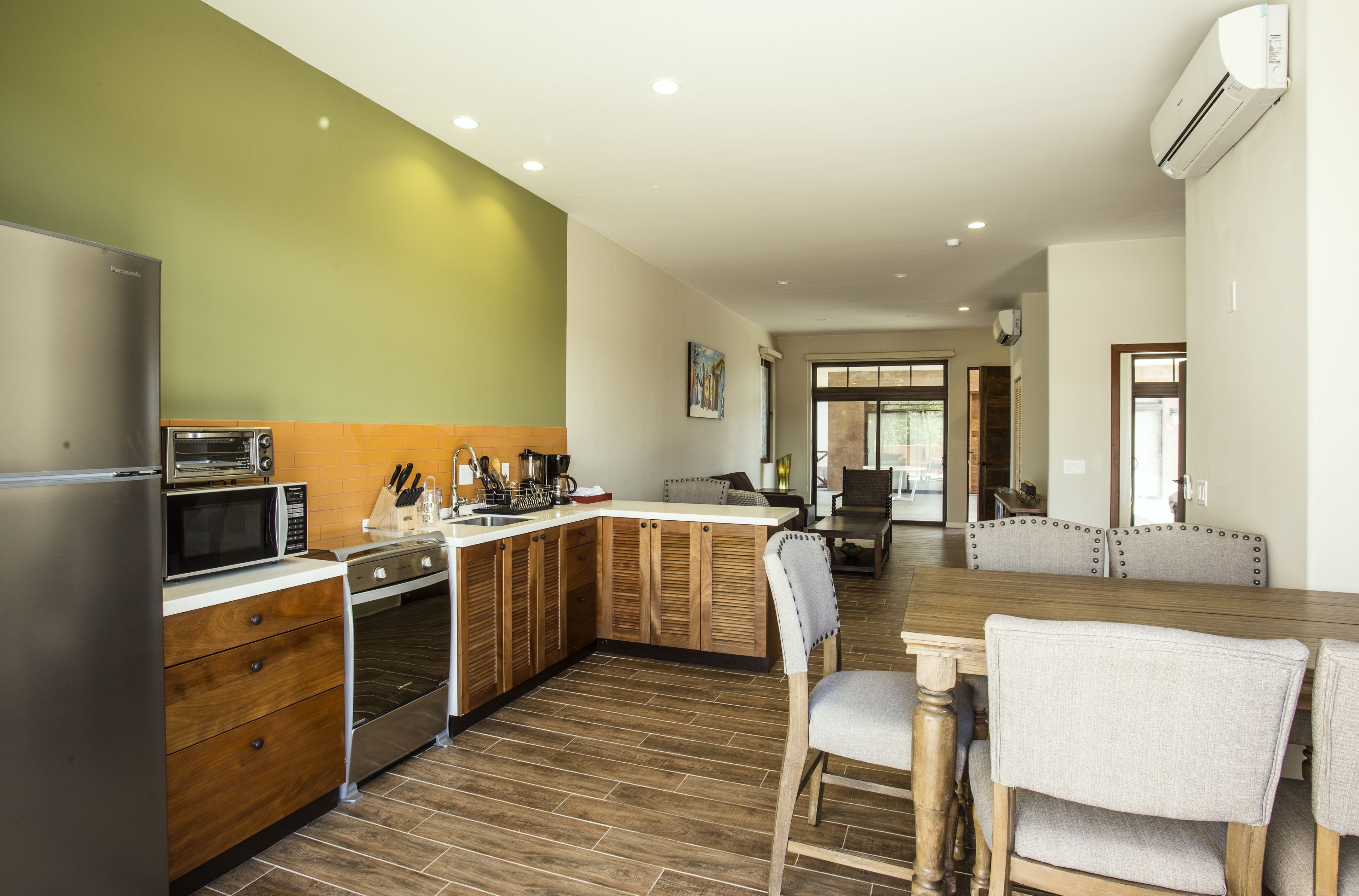 A modern kitchen with a built-in oven, microwave, and refrigerator. There is a dining area with a wooden table and chairs.