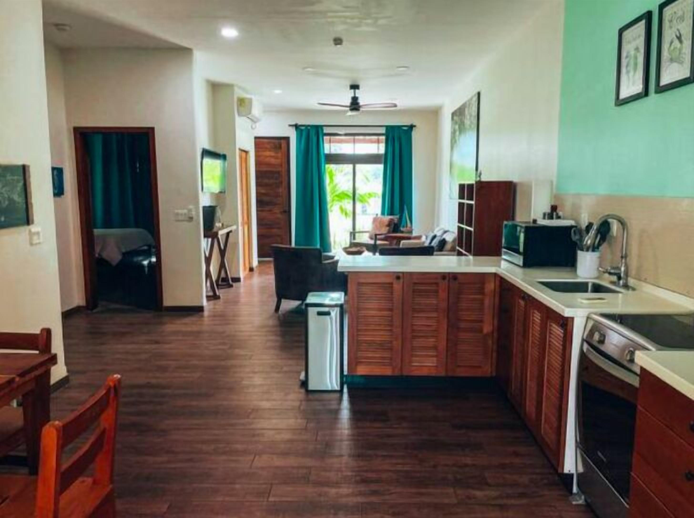 A compact kitchen with wooden cabinets, a sink, and a dining area with a table and chairs.