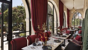 A restaurant with red upholstered booths, a chandelier, and a view of the outdoors. - Villa Brown Jerusalem (Jerusalem)
