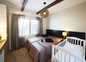Un dormitorio con una cama grande, una cuna, techo de madera y una ventana con cortinas.