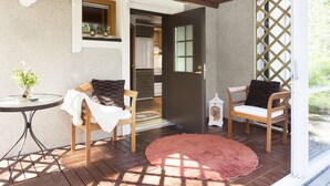 A patio area with two wooden chairs, a small round table, and a red rug. - Vuokatin Aateli Studios (Sotkamo)