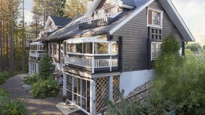 A two-story house with a balcony, a deck, and a view of the surrounding forest. - Vuokatin Aateli Studios (Sotkamo)