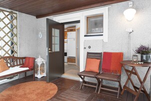 Una entrada acogedora con un banco de madera, un tapete pequeño y una puerta que da a una cocina.