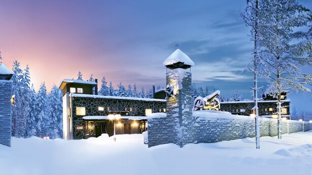 A snow-covered lodge with stone towers and a stone facade, surrounded by snow-laden trees. - Vuokatin Aateli Castle (Sotkamo)