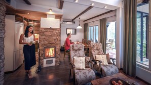 A cozy living room with a fireplace, dining area, and large windows. - Vuokatin Aateli Castle (Sotkamo)