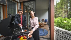 A couple grilling outdoors with a view of a balcony and a dining area. - Vuokatin Aateli Castle (Sotkamo)