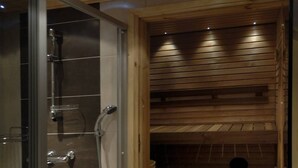 A sauna with a wooden bench and a glass-enclosed shower area. - Vuokatin Aateli Castle (Sotkamo)