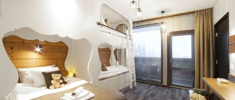 A hotel room with a bunk bed, a desk, a chair, a window with curtains, and a balcony.