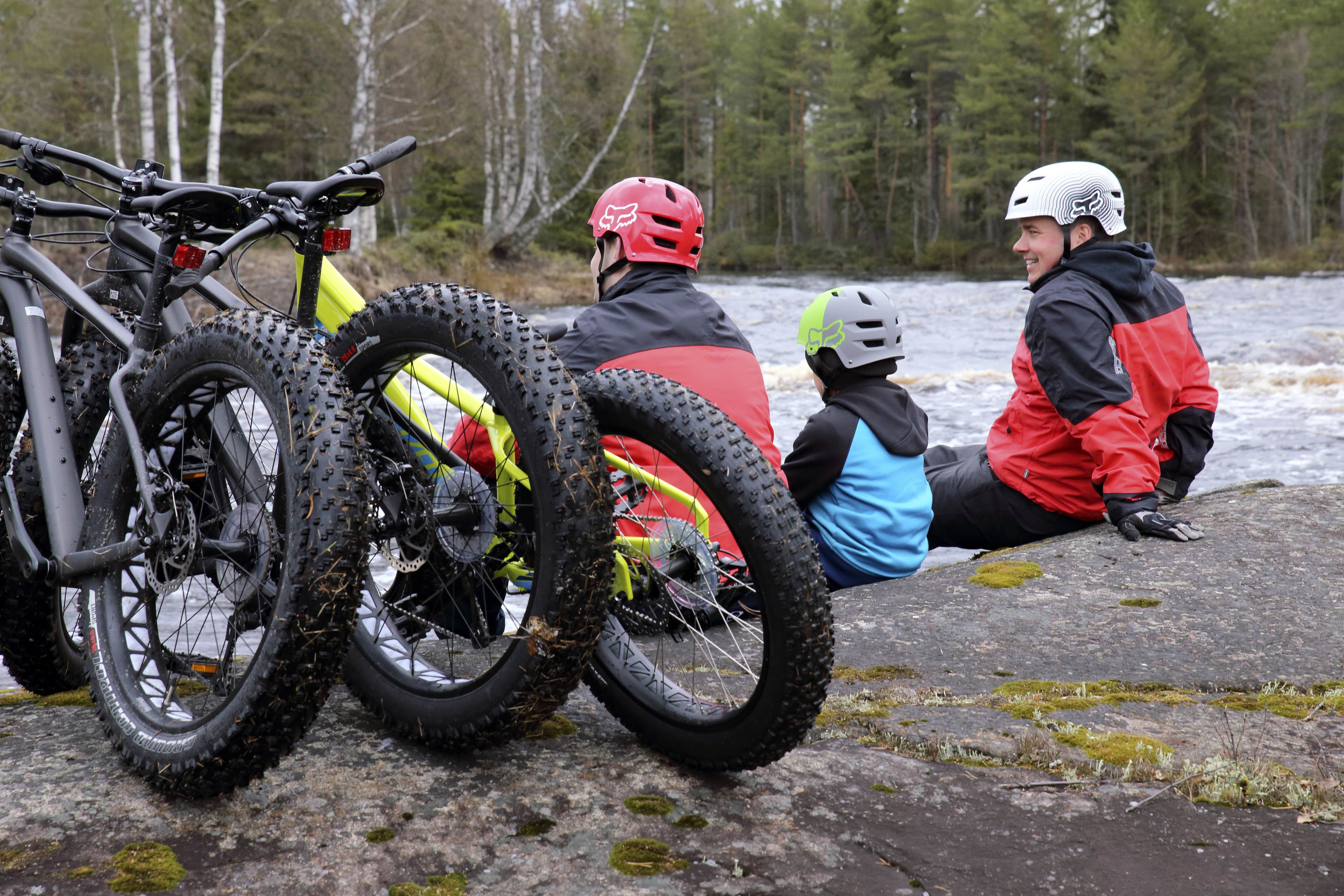 Two people sitting on a rock with bicycles beside them.