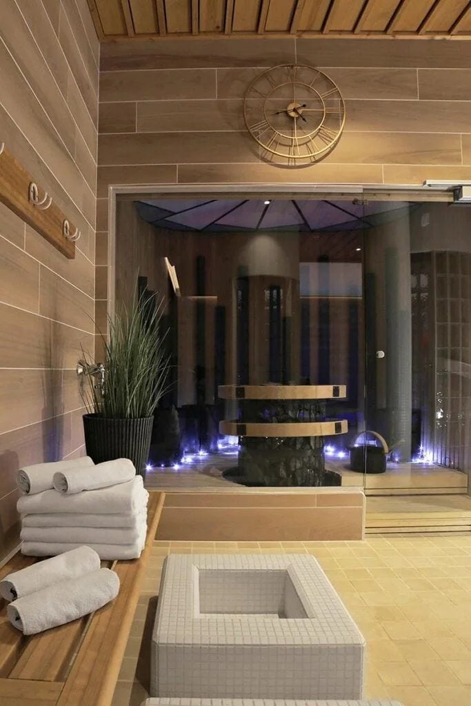 Un moderno espacio de spa con zona de estar, un reloj grande y una fuente de agua.