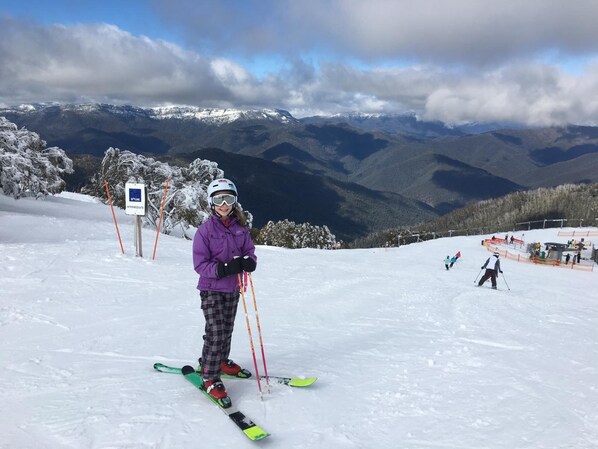 A person skiing on a snowy slope with a mountainous backdrop. - Terama Ski Lodge (Mount Buller)