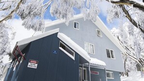 A building with a blue exterior, a sign warning of falling snow and ice, and a nameplate reading "TERAMA". - Terama Ski Lodge (Mount Buller)