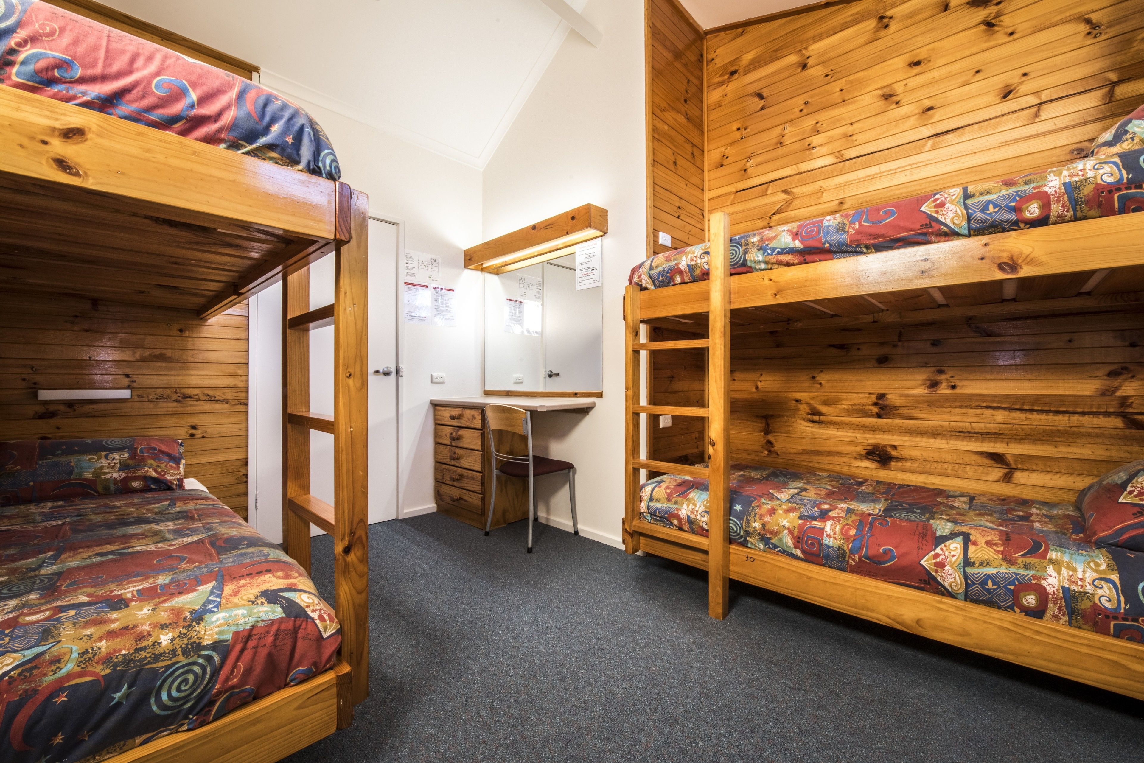 A dormitory room with bunk beds, a desk, and a chair.
