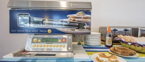 Una estación autoservicio para panqueques con pantalla digital y botones, una tostadora y una cesta de pan.