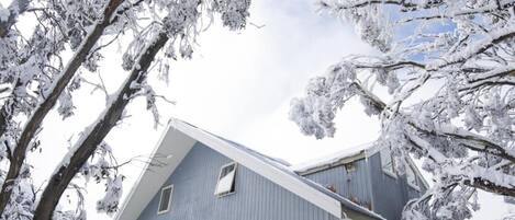 A two-story building with a sloped roof, surrounded by snow-covered trees.