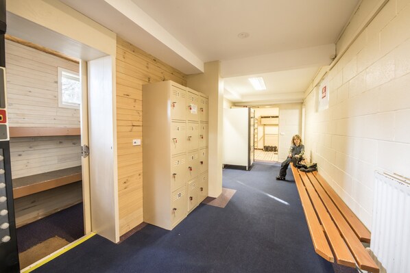 A hallway with lockers, a bench, and a door leading to another room. - Terama Ski Lodge (Mount Buller)