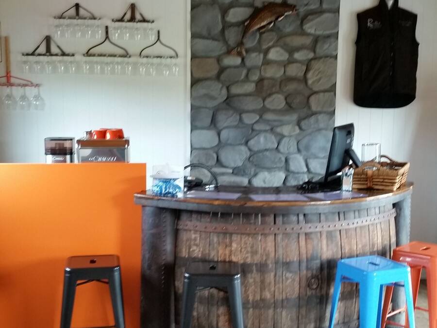 A rustic bar area with a stone wall, wooden ceiling, and stools.