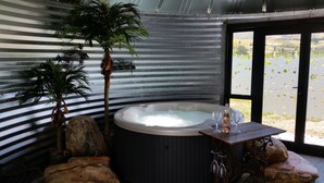 Un jacuzzi con vistas a un lago, rodeado de rocas y plantas en macetas.
