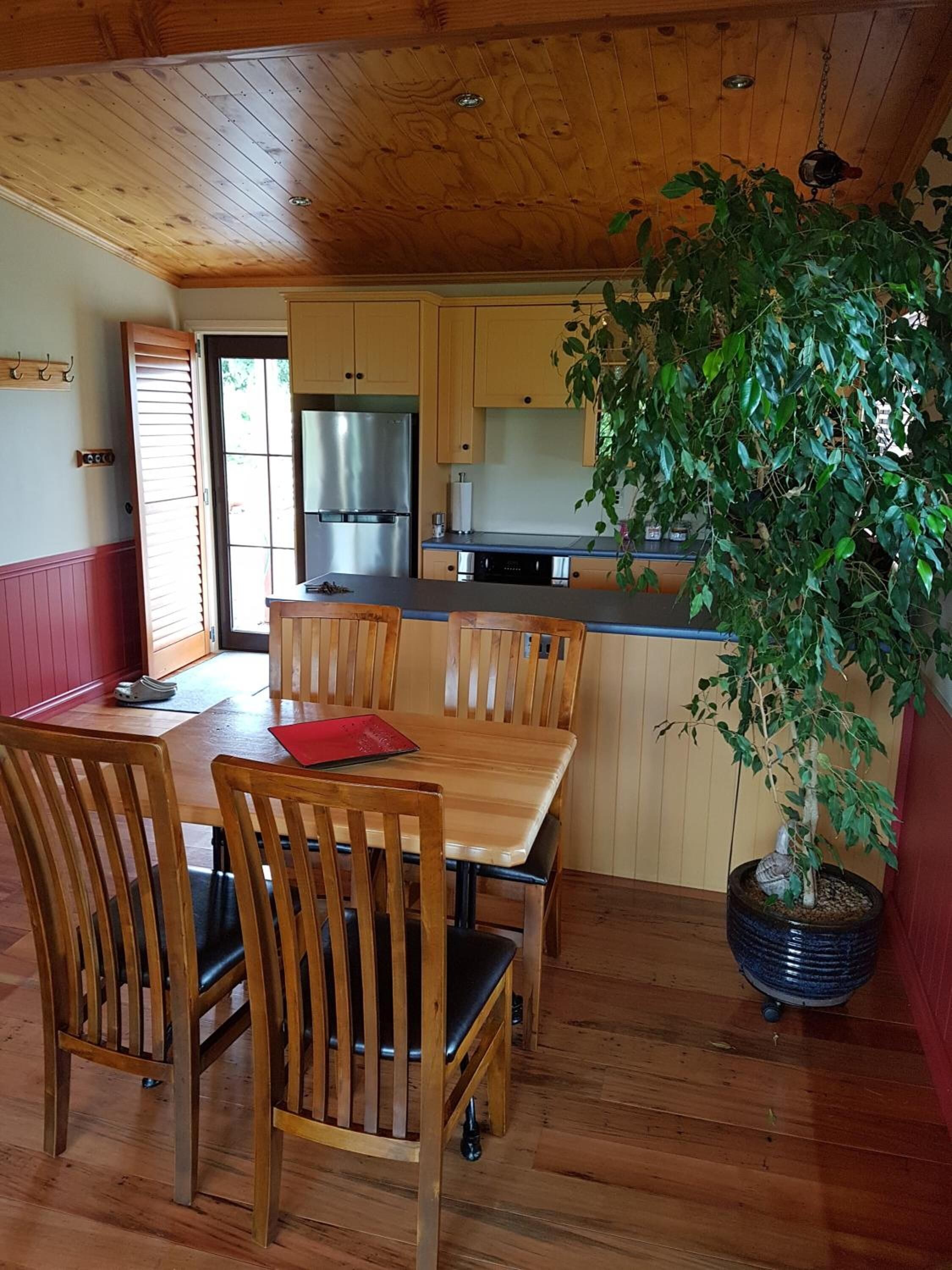 Un interior de madera con comedor, cocina y una planta en maceta.