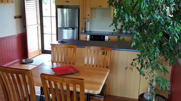 Un interior de madera con comedor, cocina y una planta en maceta.