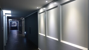 A modern hallway with recessed lighting, dark walls, and a dark floor. - Gallery Hotel BnB (Jeju City)
