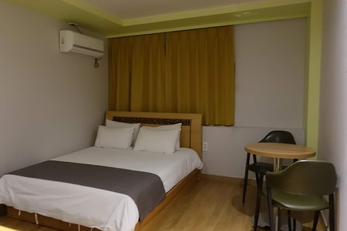 A hotel room with a bed, a small table, and a chair.