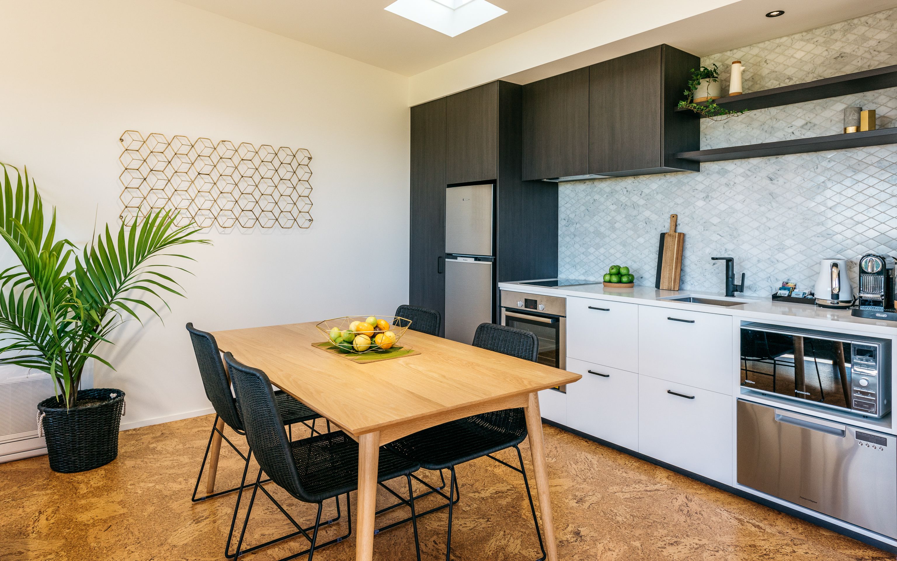 A modern kitchen with a wooden dining table, black chairs, and a built-in oven.