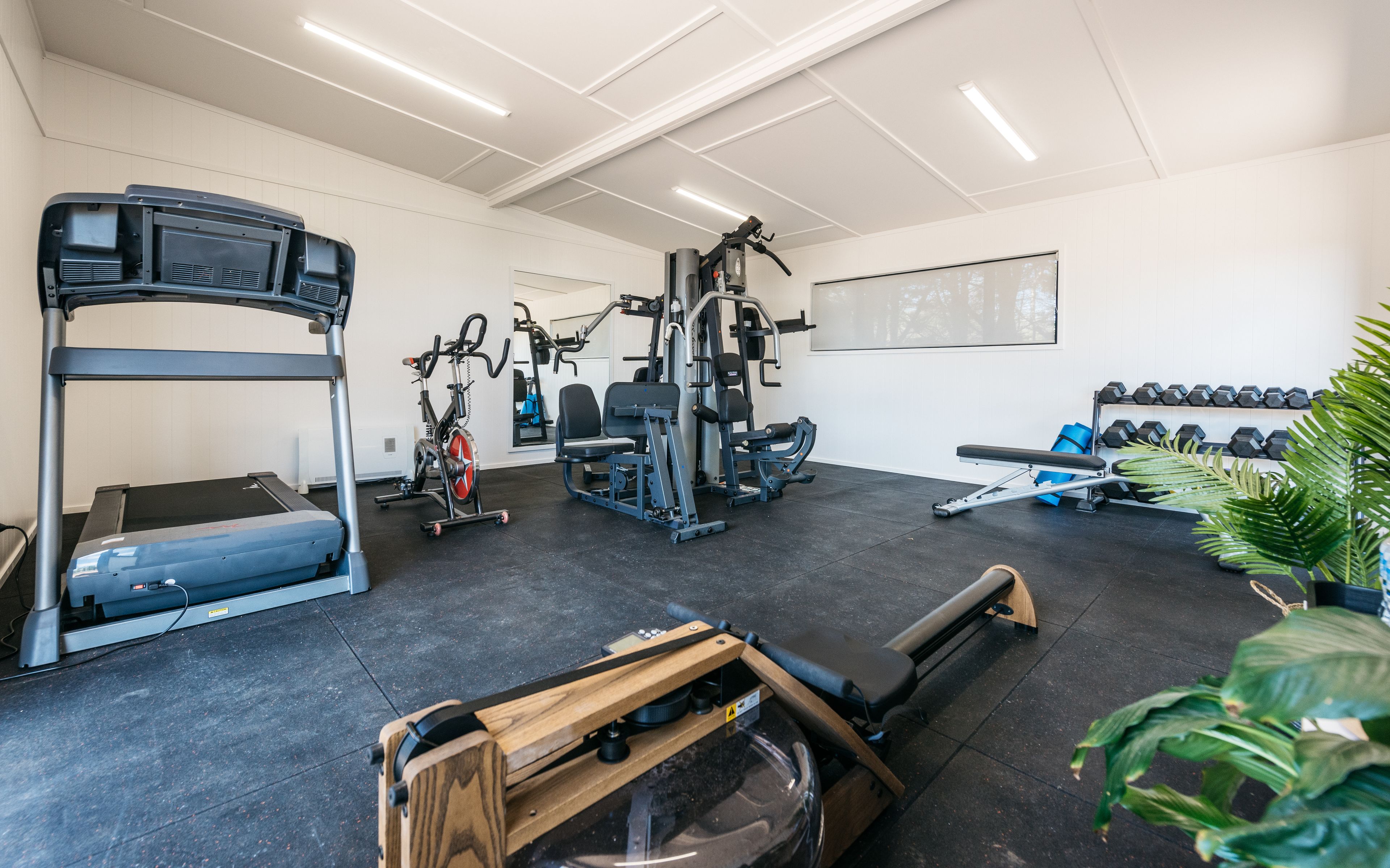 Une salle de sport équipée de tapis de course, de vélos elliptiques, d’appareils de musculation et d’haltères.