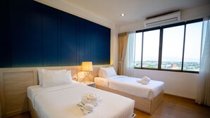 Quarto de hotel com duas camas, uma janela grande com vista para a cidade e um aparelho de ar condicionado.