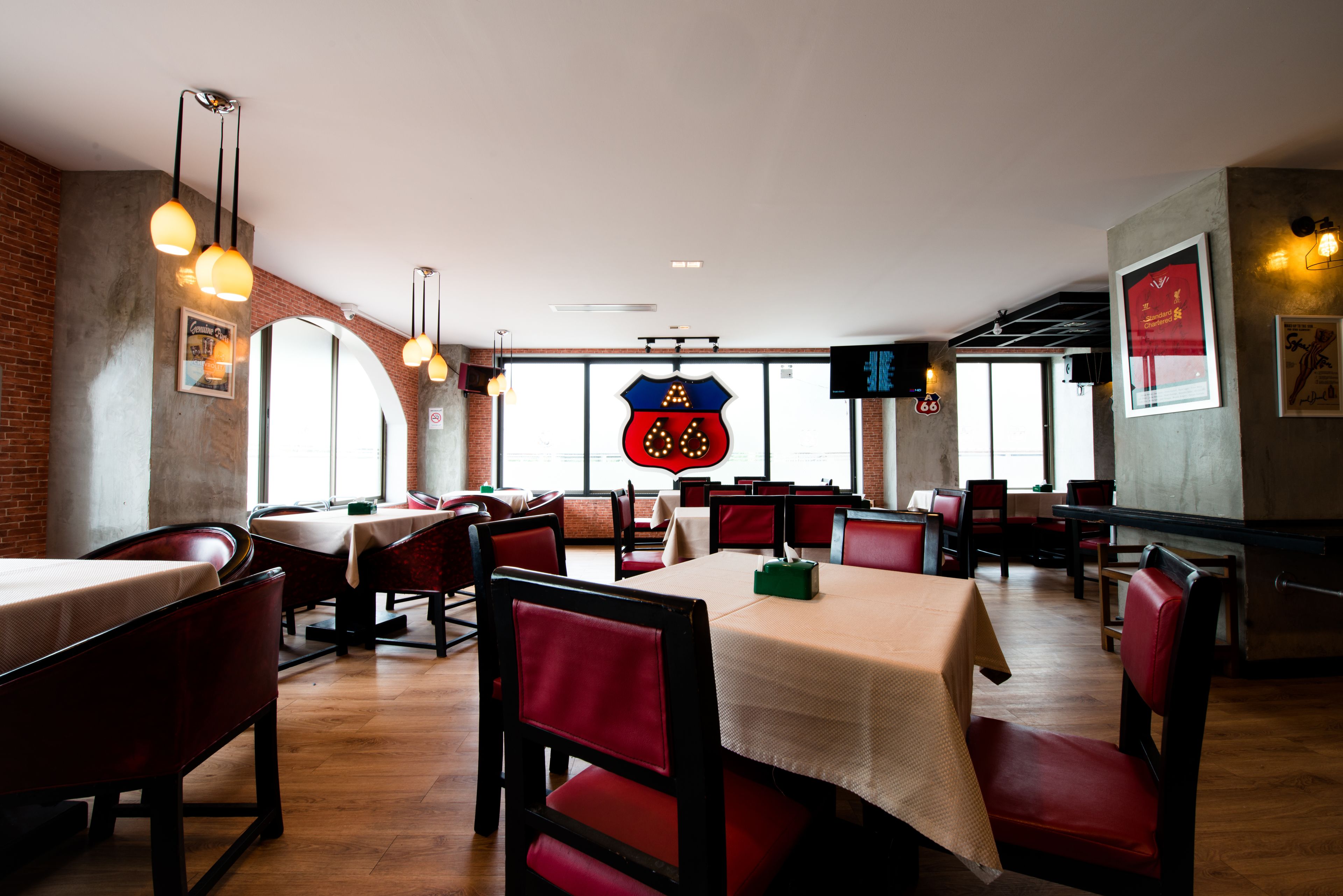 Ein Restaurantinnenraum mit Ziegelwänden, Holzböden, rot gepolsterten Stühlen und Tischen mit weißen Tischdecken.