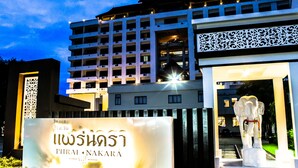 Entrada de hotel com uma placa indicando "PHIRAL NAKARA" e uma estátua de elefante.