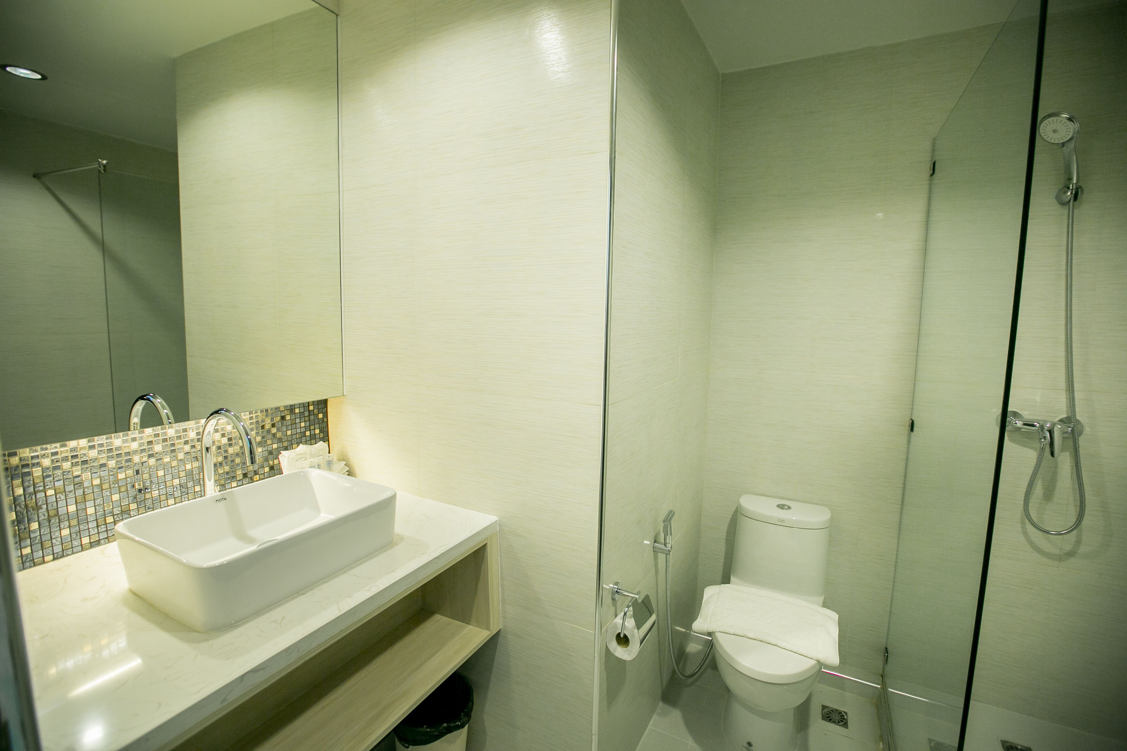 Un baño moderno con un lavamanos grande y blanco, una cabina de ducha de vidrio y un inodoro.