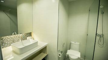 Un baño moderno con un lavamanos grande y blanco, una cabina de ducha de vidrio y un inodoro.