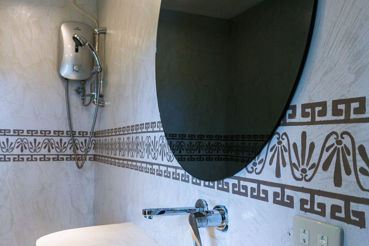 A bathroom with a freestanding bathtub, a wall-mounted mirror, and a showerhead.