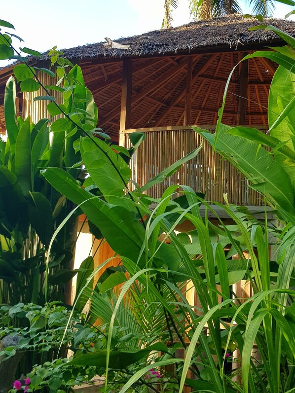 Una edificación con techo de paja rodeada de exuberante vegetación.