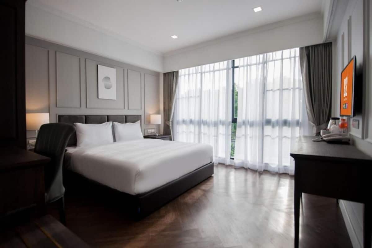 Una habitación de hotel moderna con una cama grande, un escritorio, una silla y un televisor.