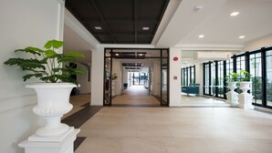 Un moderno vestíbulo de hotel con un corredor central, plantas en macetas y amplias ventanas.