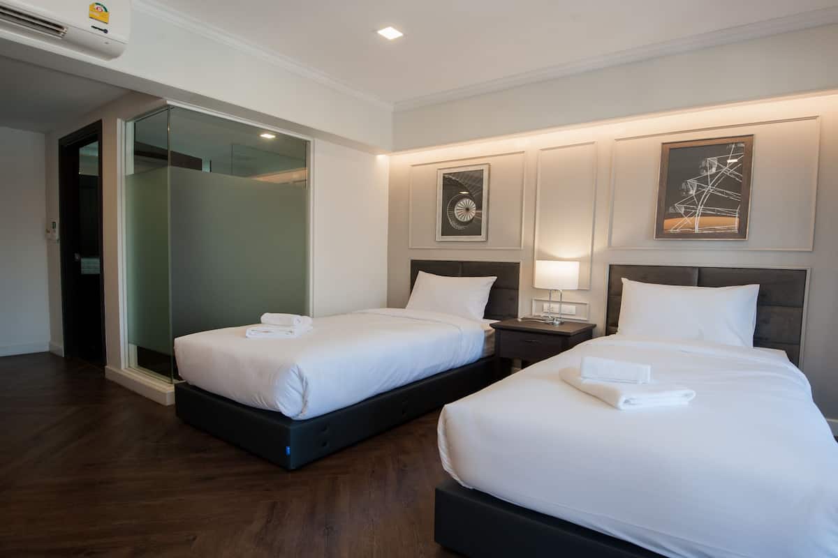 Habitación de hotel con dos camas, una puerta de cristal y obras de arte en las paredes.