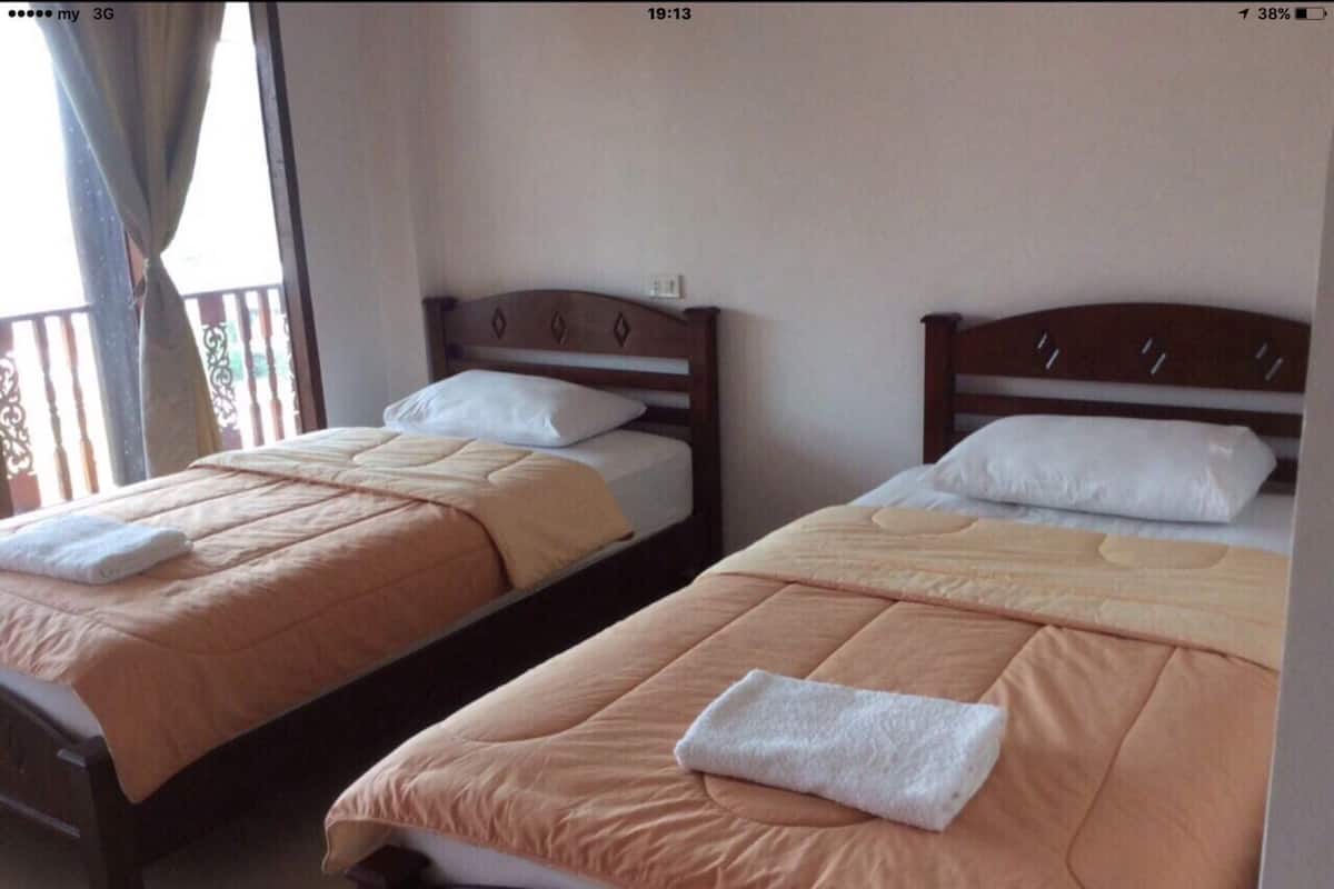 Dos camas individuales con cabeceros de madera, ropa de cama color beige y almohadas blancas.