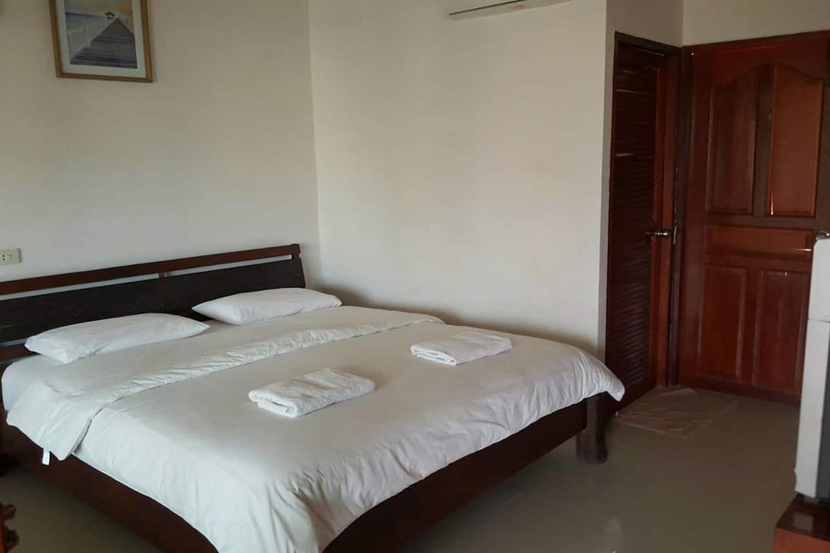 Habitación de hotel con una cama grande, cabecero de madera, ropa de cama blanca y una puerta de madera.