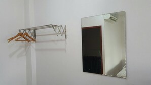 A mirror with a wooden door reflection, a metal rack with hangers, and a white wall. - Sweet Home Chiang Khan (Chiang Khan)