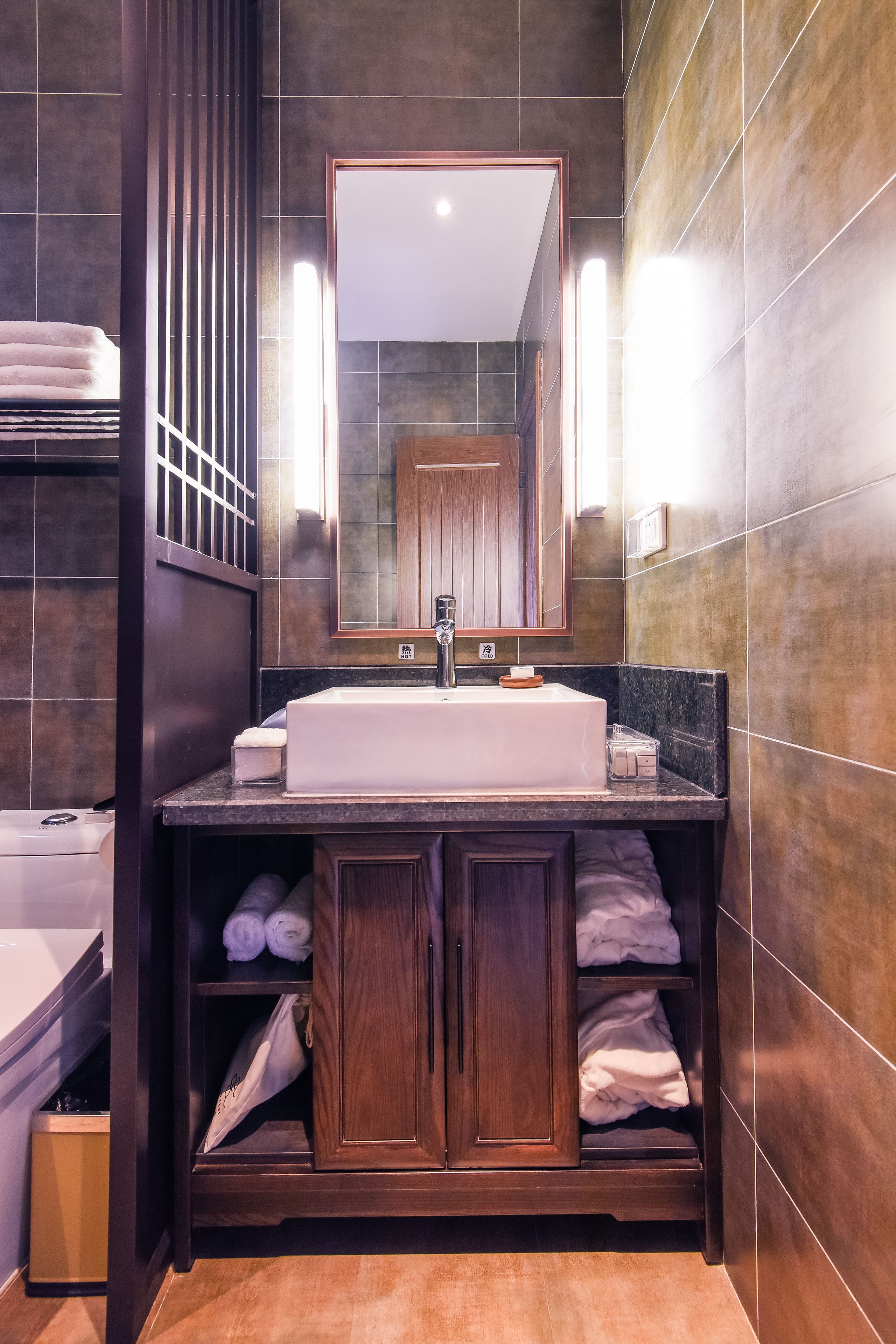 A modern bathroom with a large mirror, a white sink, and built-in shelves for towels.