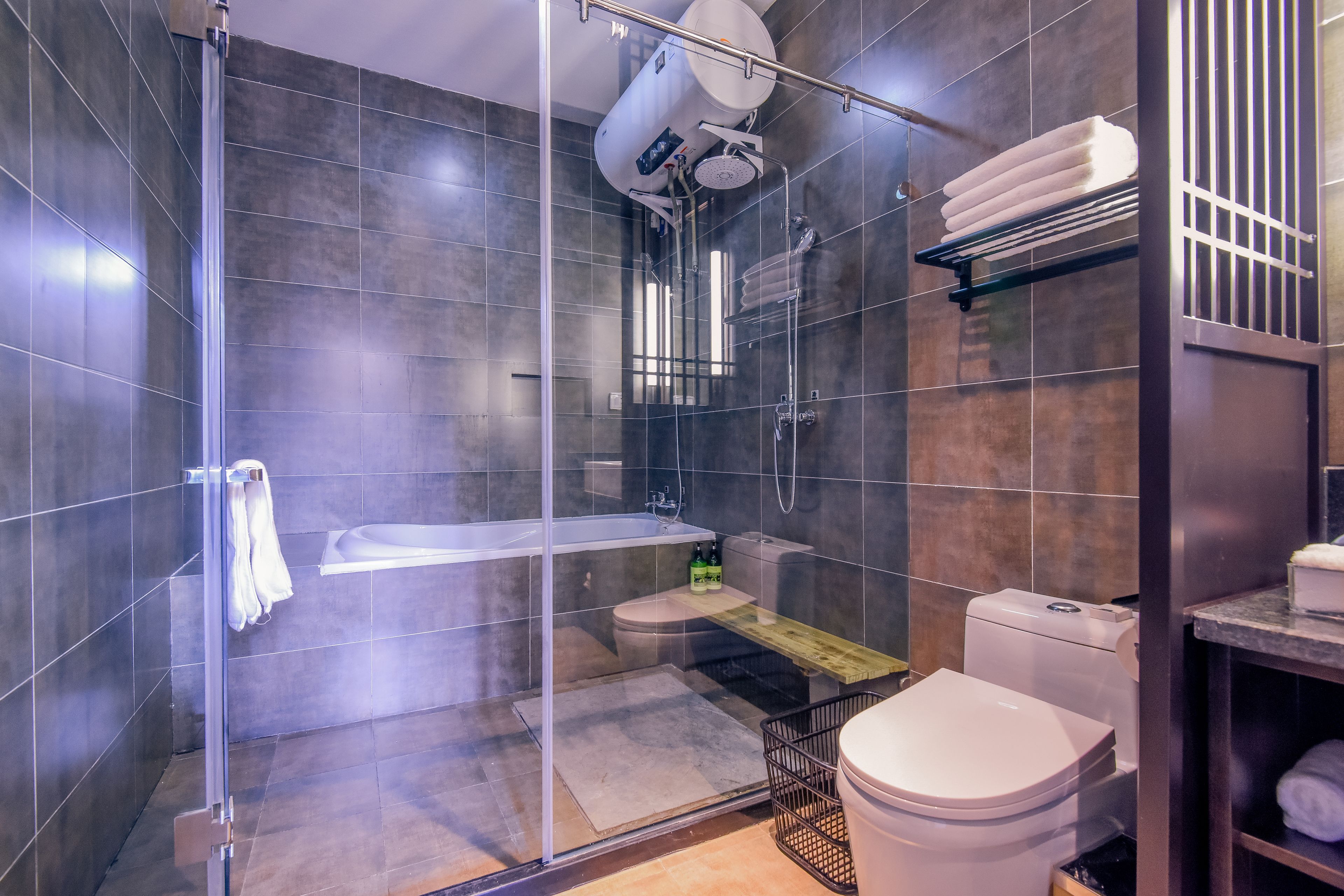 A modern bathroom with a glass-enclosed shower, a white bathtub, and a toilet.