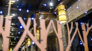 Um interior moderno com teto de madeira, luminárias pendentes decorativas e parede texturizada.