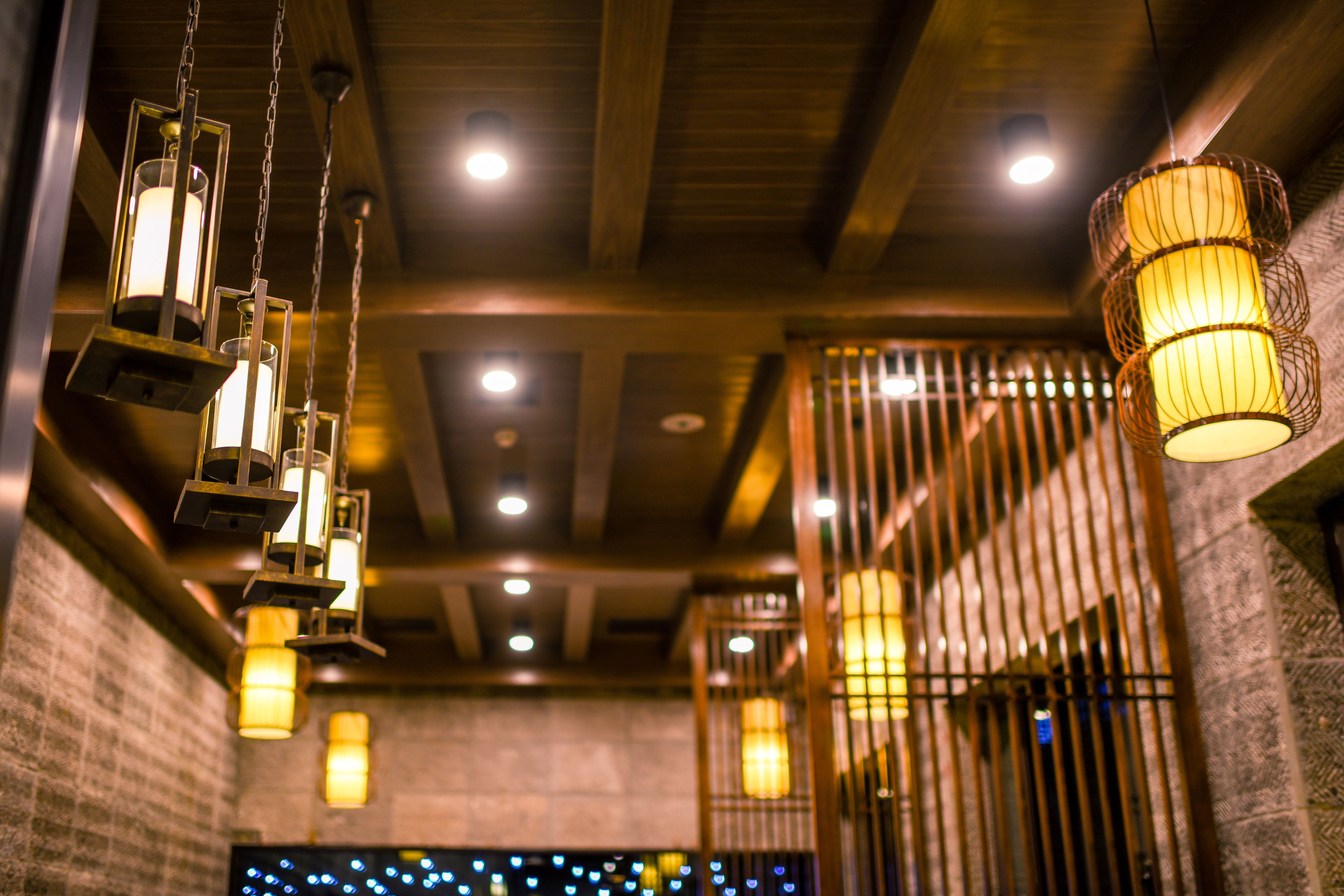 A room with hanging lantern-style lights, a brick wall, and a metal gate.