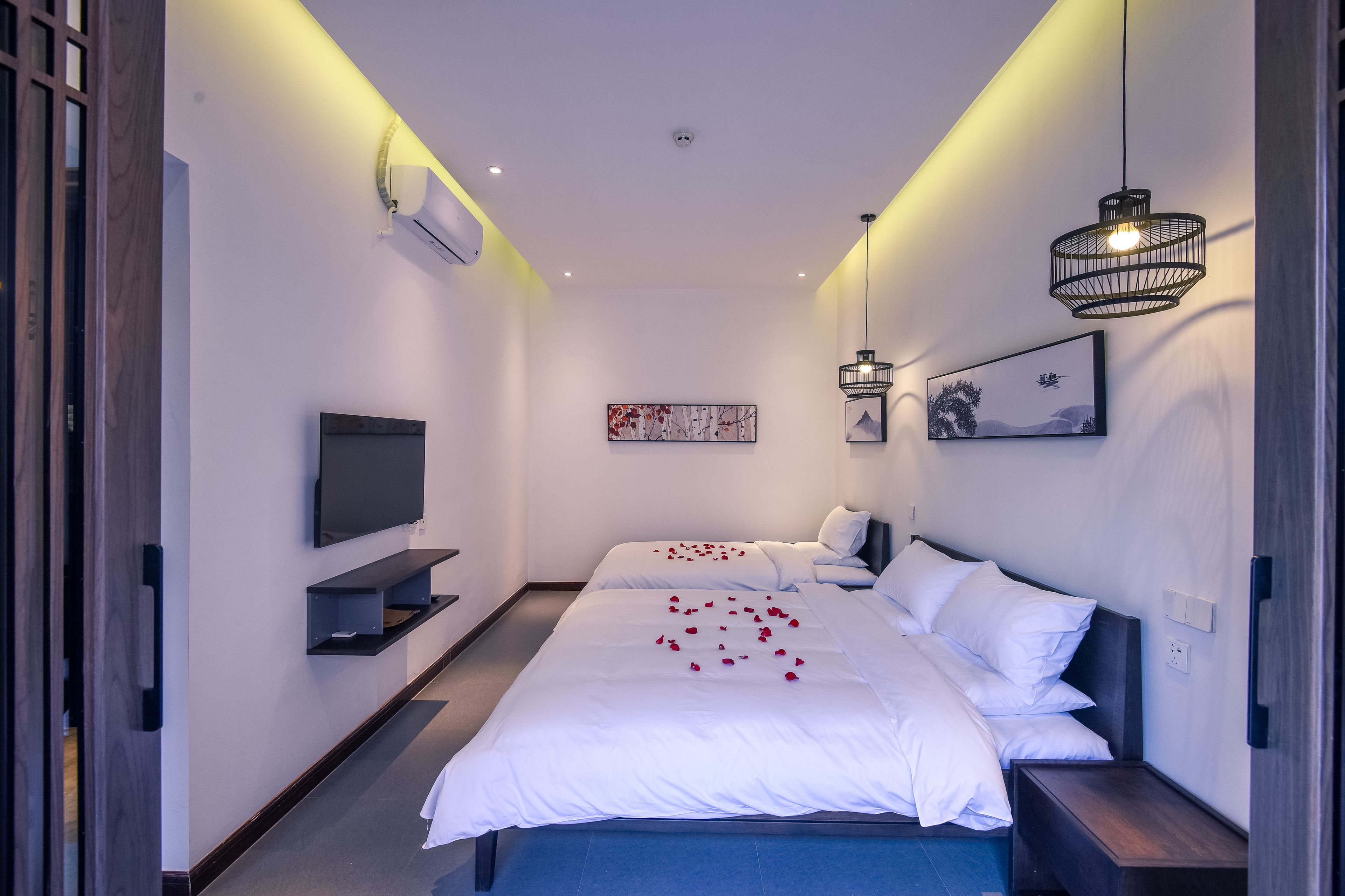 Habitación de hotel moderna con una cama grande, un televisor de pantalla plana, aire acondicionado de pared y una lámpara empotrada en el techo.