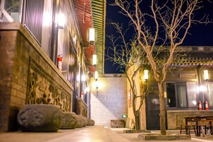Un edificio tradicional con esculturas de piedra, un árbol y una mesa de madera afuera de noche.