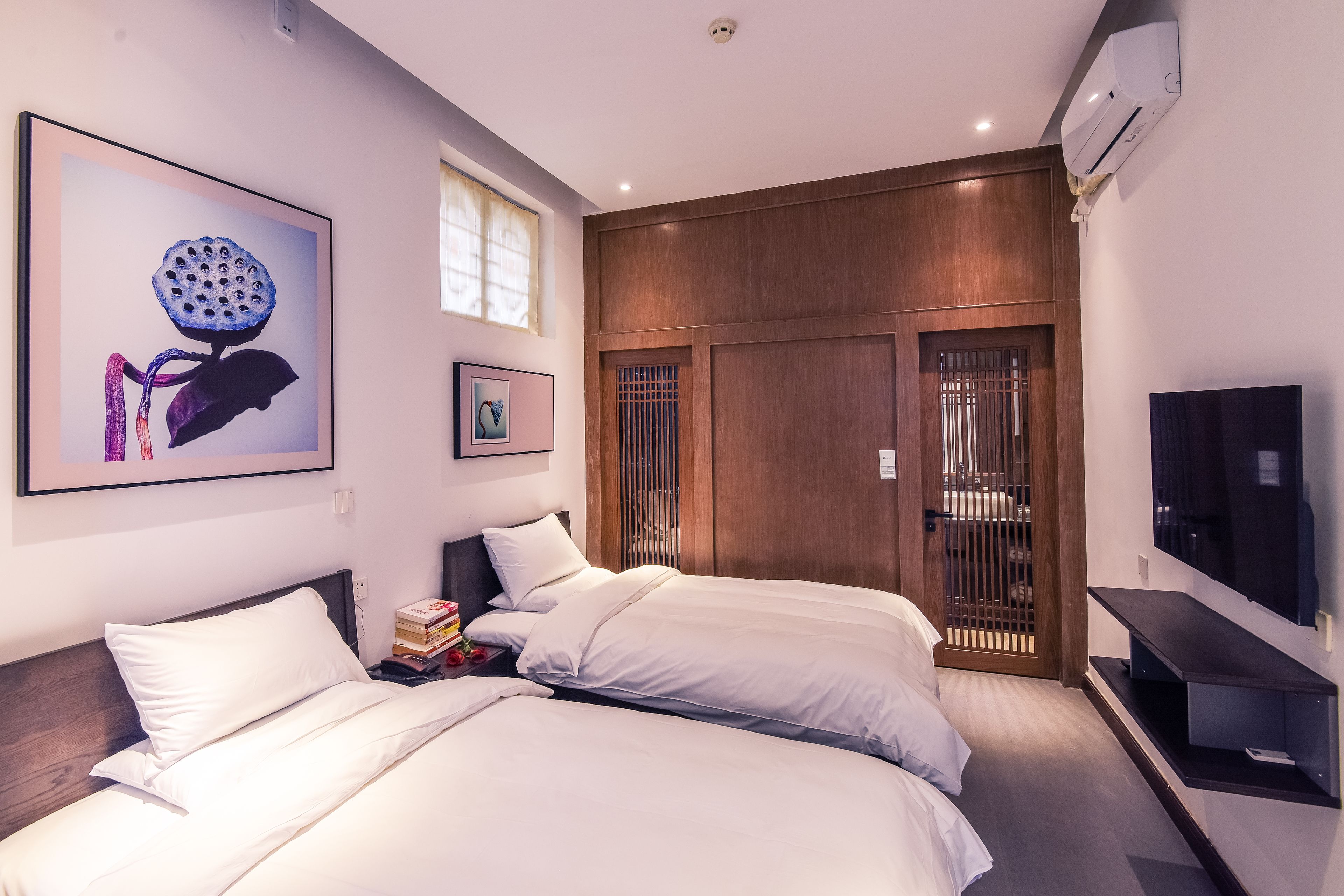 Habitación de hotel con dos camas, televisión y obras de arte en las paredes.