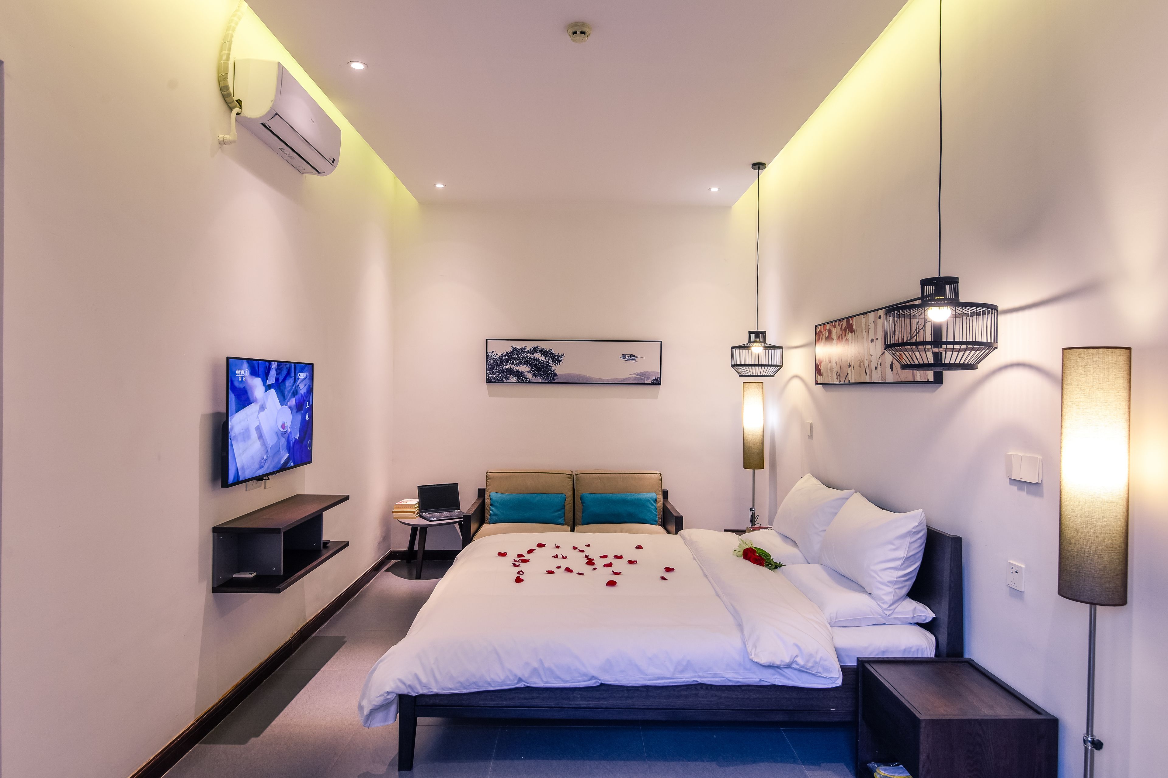 Una habitación de hotel moderna con cama, televisor, escritorio y aire acondicionado instalado en la pared.