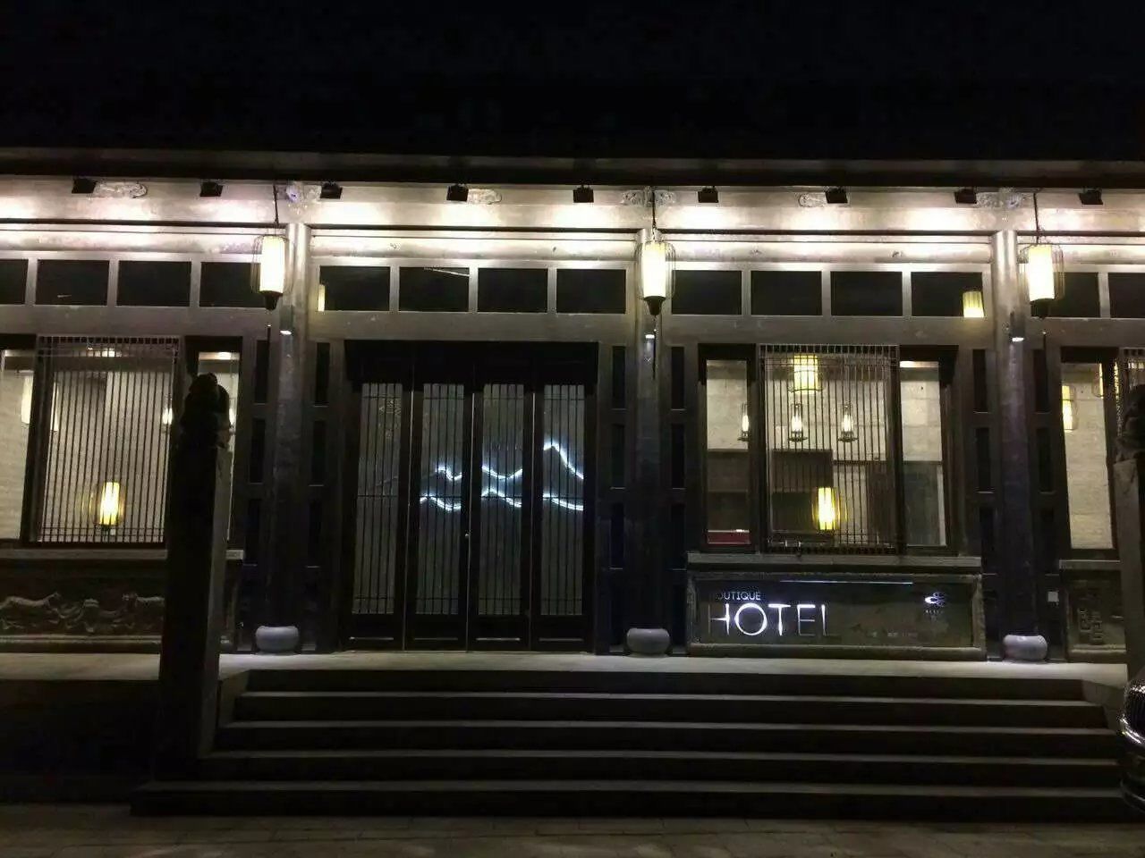 A hotel entrance with a modern design, featuring a prominent 'HOTEL' sign and a staircase leading to the entrance.
